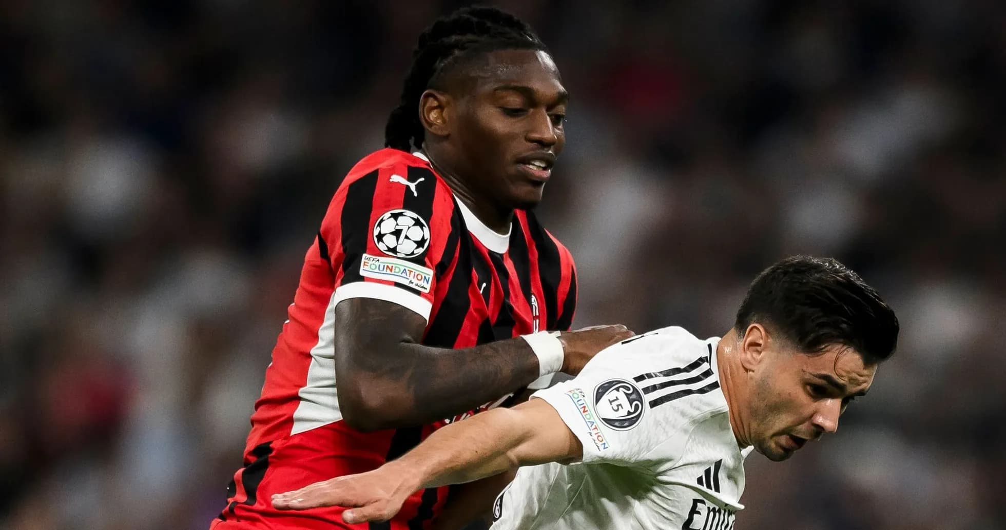 Joueur en maillot noir et rouge pousse adversaire en blanc
