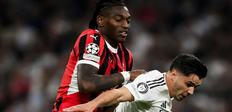Joueur en maillot noir et rouge pousse adversaire en blanc
