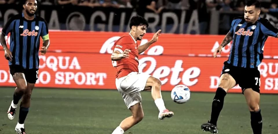 Joueur en rouge dribblant le ballon entre deux adversaires