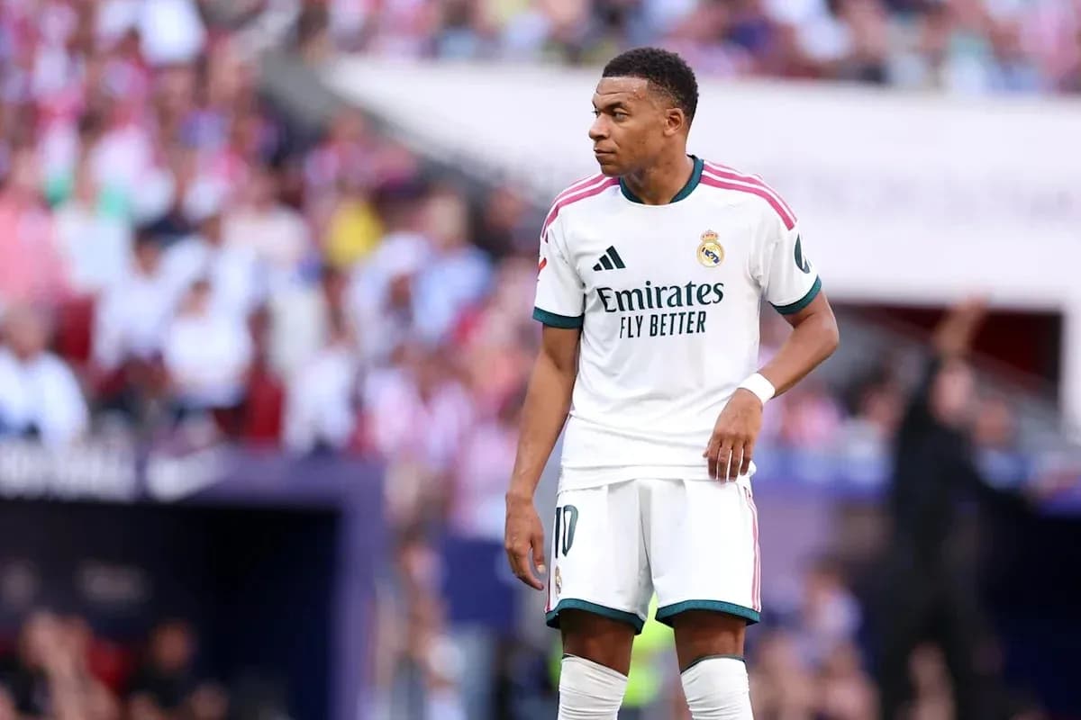 Kylian Mbappé debout sur le terrain avec des supporters en arrière-plan