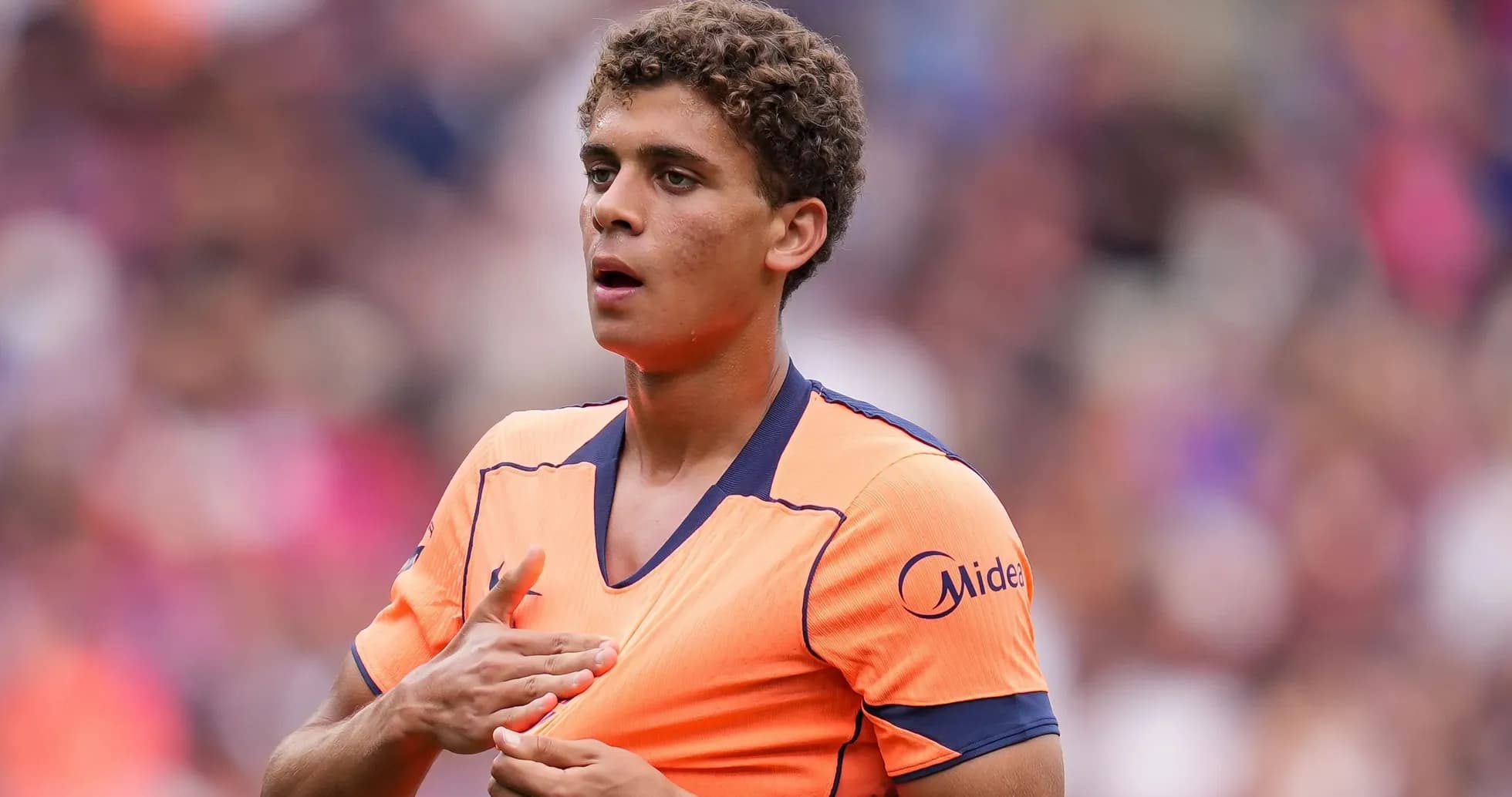 Joueur en tenue orange sur le terrain de football