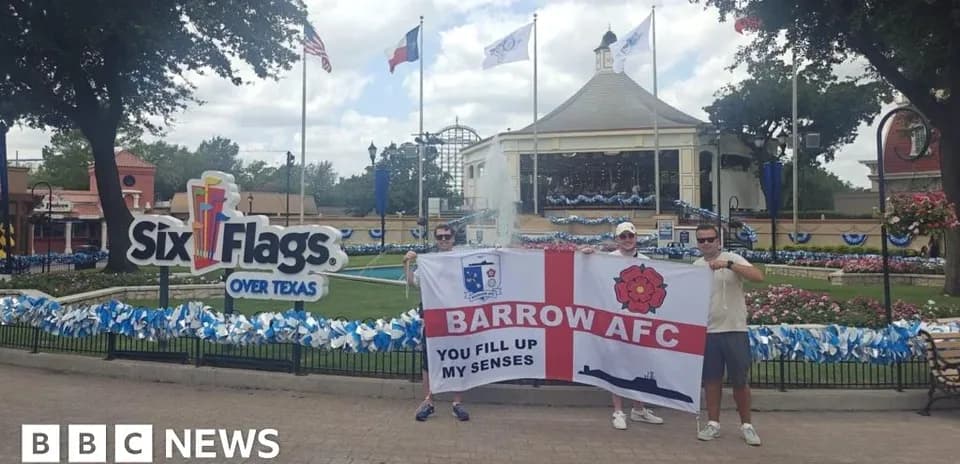 Supporters holding Barrow AFC flag at amusement park