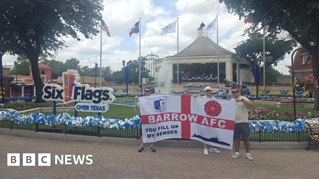 Supporters holding Barrow AFC flag at amusement park