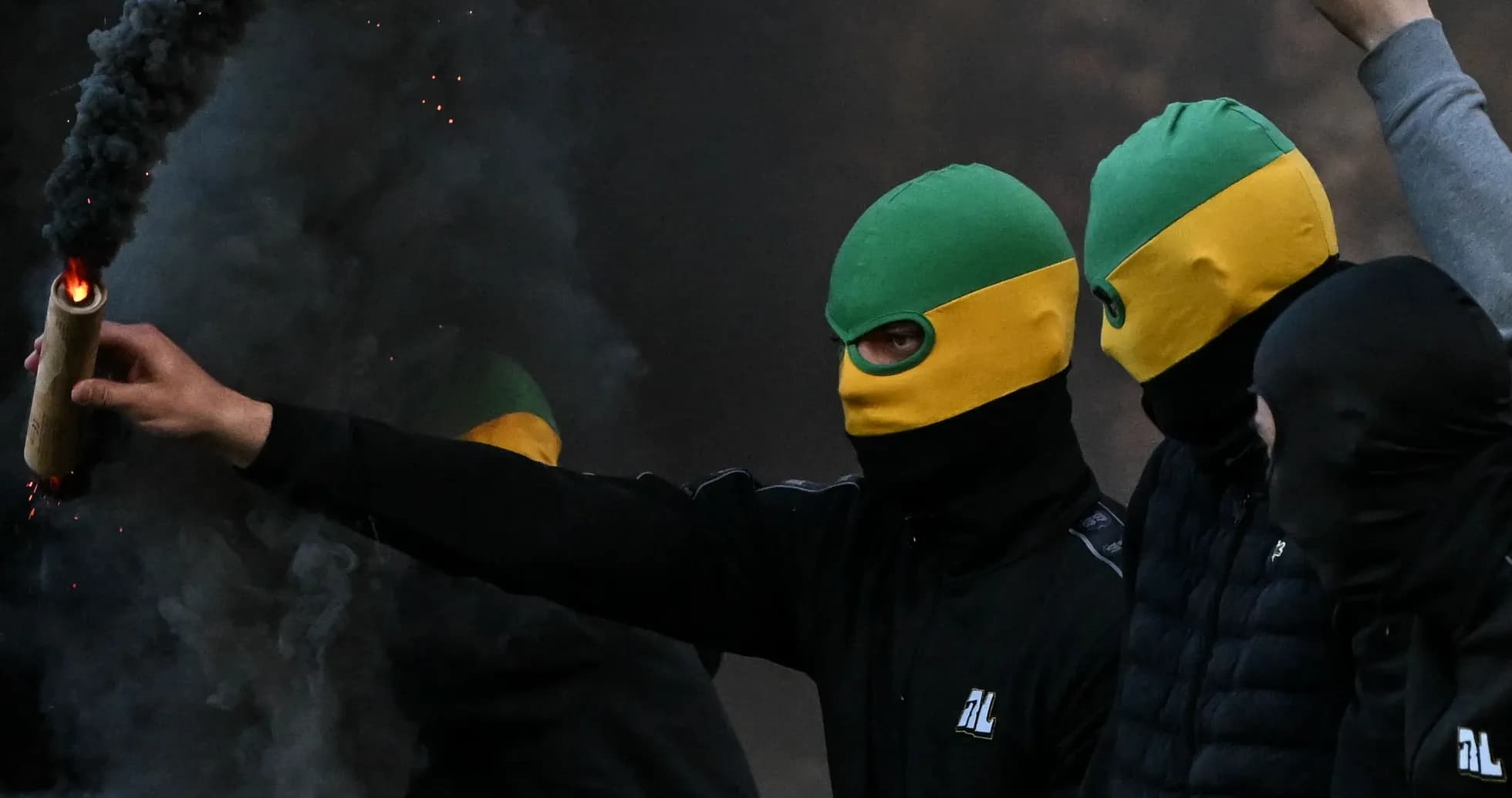 Supporters wearing masks and holding a flare