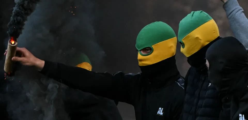 Supporters wearing masks and holding a flare