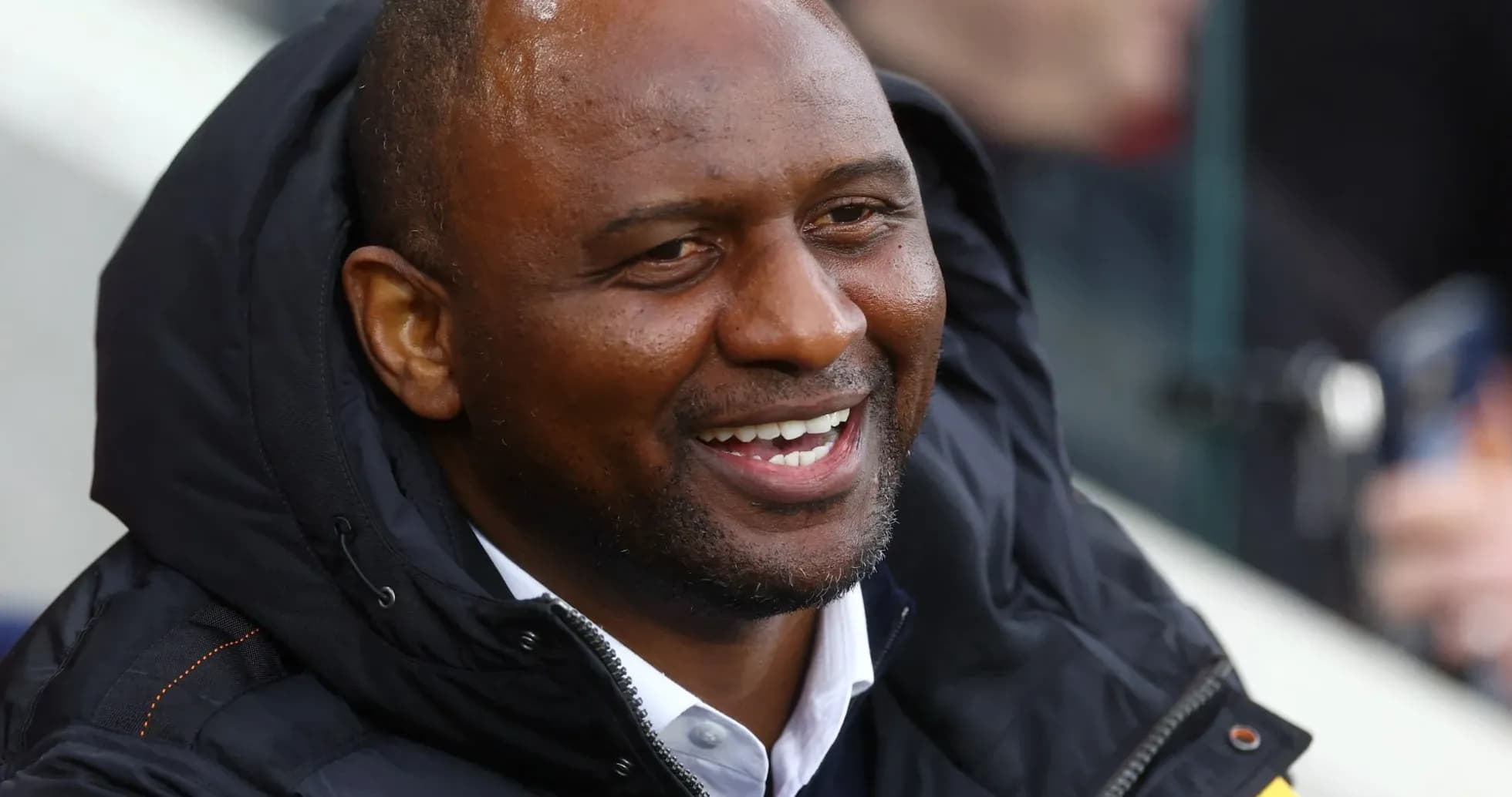 Homme souriant en veste lors d'un match
