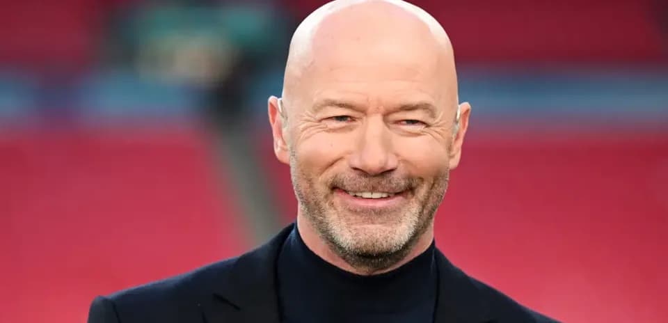 Homme souriant en costume sur un terrain de football