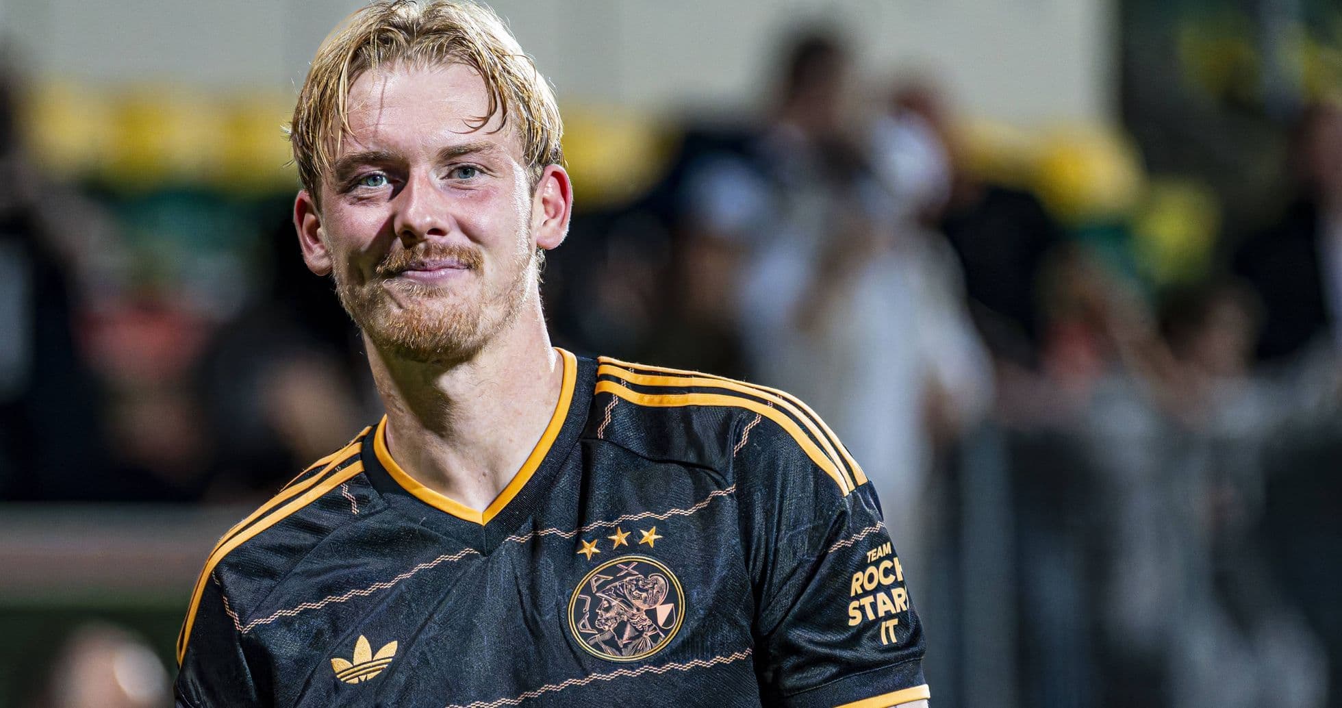 Joueur d'Ajax en maillot noir souriant après le match