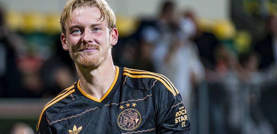 Joueur d'Ajax en maillot noir souriant après le match
