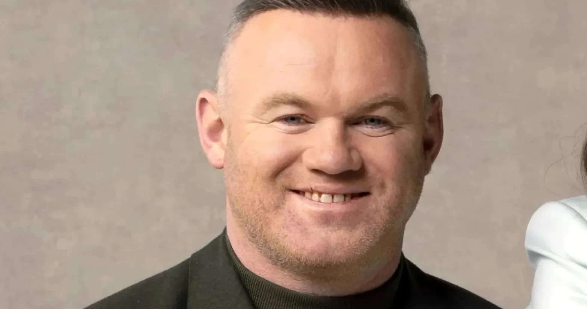 Homme souriant avec une veste noire sur fond neutre