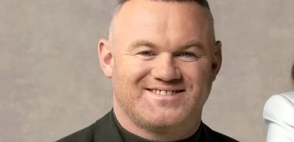Homme souriant avec une veste noire sur fond neutre