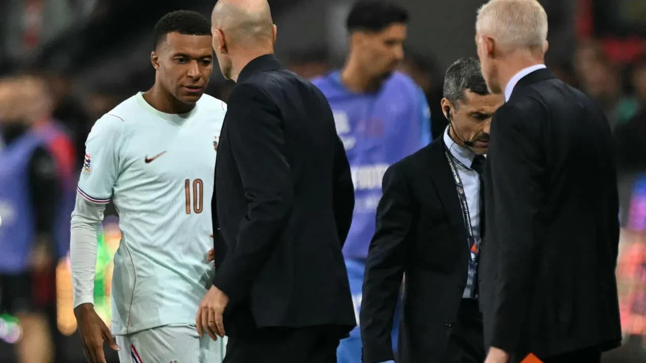 Kylian Mbappé conversing with coaches on the sideline