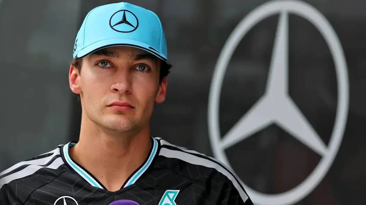Pilote en tenue Mercedes devant le logo de l'équipe Pilote en tenue Mercedes devant le logo de l'équipe