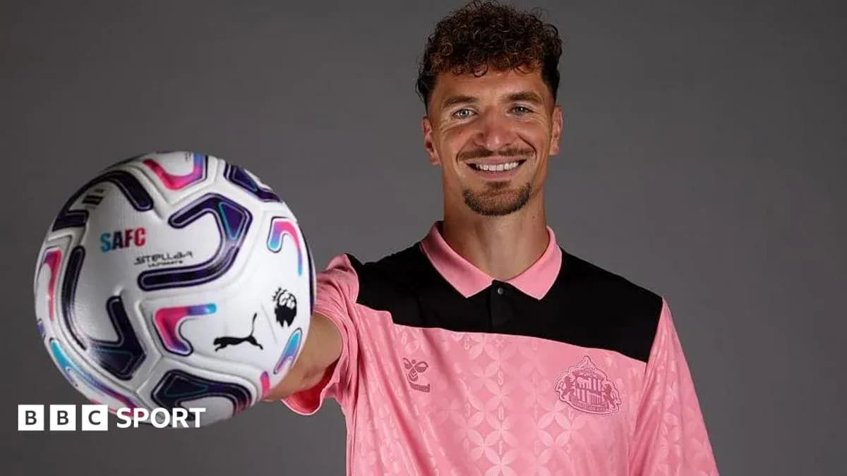 Joueur tenant un ballon de football en souriant Joueur tenant un ballon de football en souriant