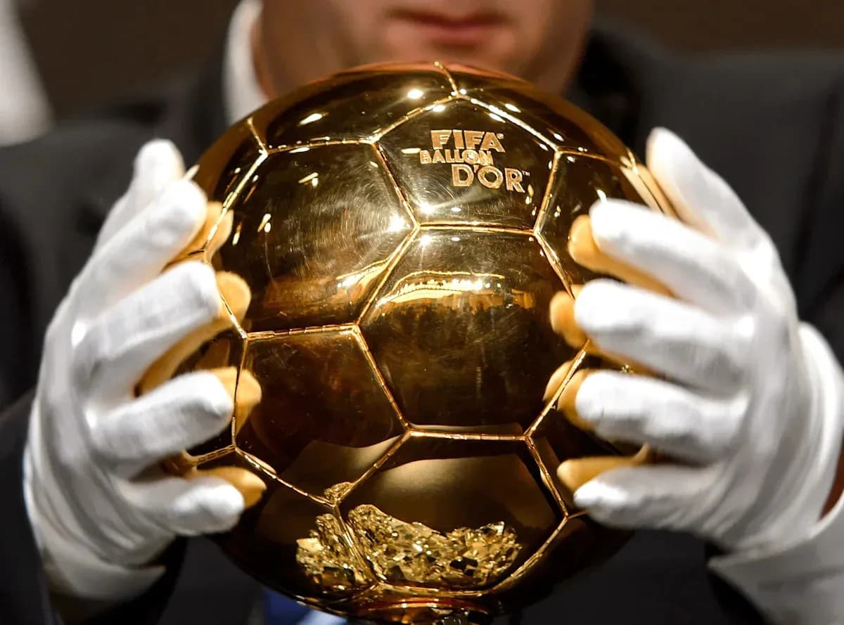 Trophée Ballon d'Or tenu par des mains gantees Trophée Ballon d'Or tenu par des mains gantees