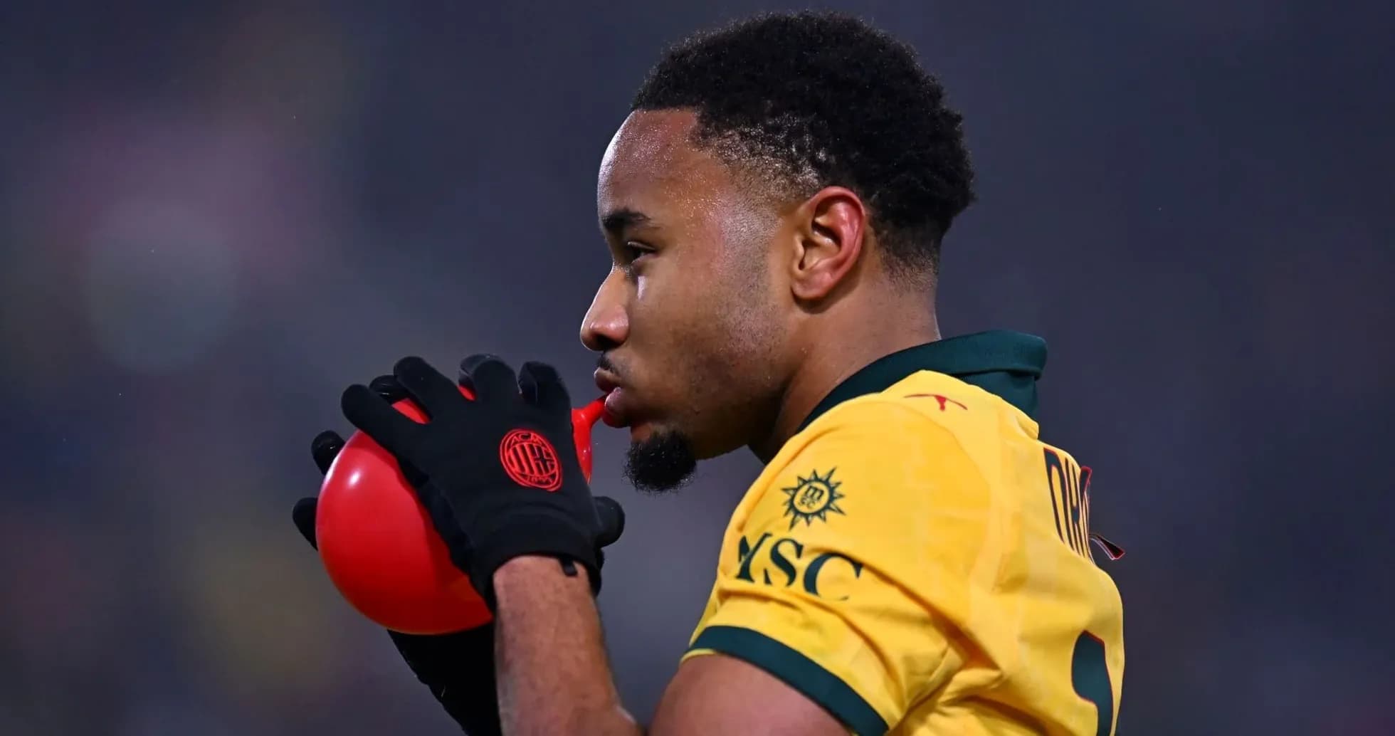 Joueur soufflant dans un ballon rouge pendant un match Joueur soufflant dans un ballon rouge pendant un match