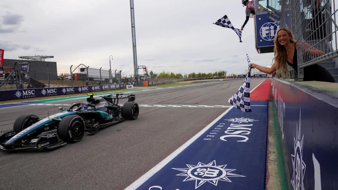 Voiture de F1 franchissant la ligne d'arrivée avec drapeaux à damiers Voiture de F1 franchissant la ligne d'arrivée avec drapeaux à damiers