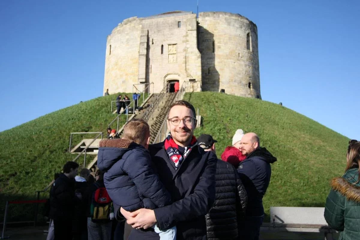 Homme tenant un enfant devant une forteresse Homme tenant un enfant devant une forteresse