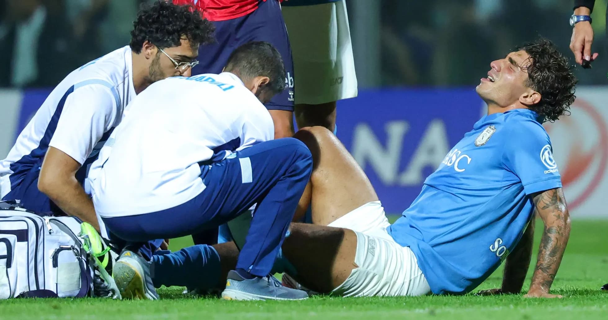 Joueur blessé avec deux entraîneurs sur le terrain Joueur blessé avec deux entraîneurs sur le terrain