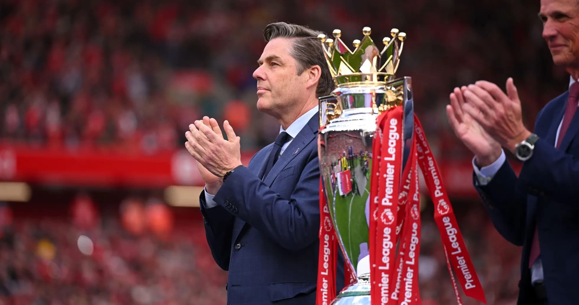 Homme applaudissant près du trophée de la Premier League Homme applaudissant près du trophée de la Premier League