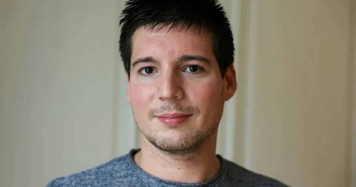 Homme souriant avec un t-shirt gris devant un mur Homme souriant avec un t-shirt gris devant un mur