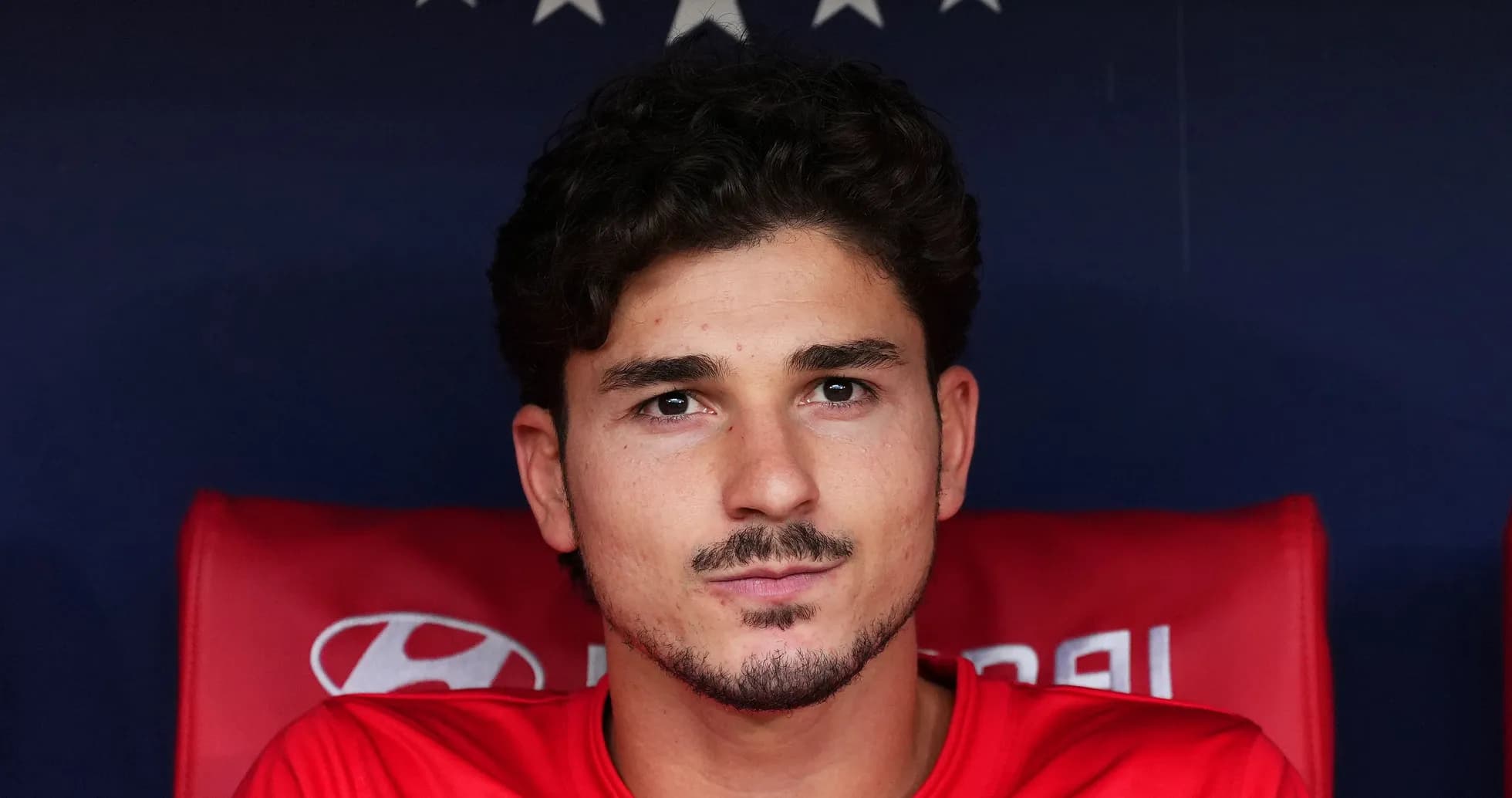 Joueur assis sur le banc de touche, regard sérieux Joueur assis sur le banc de touche, regard sérieux