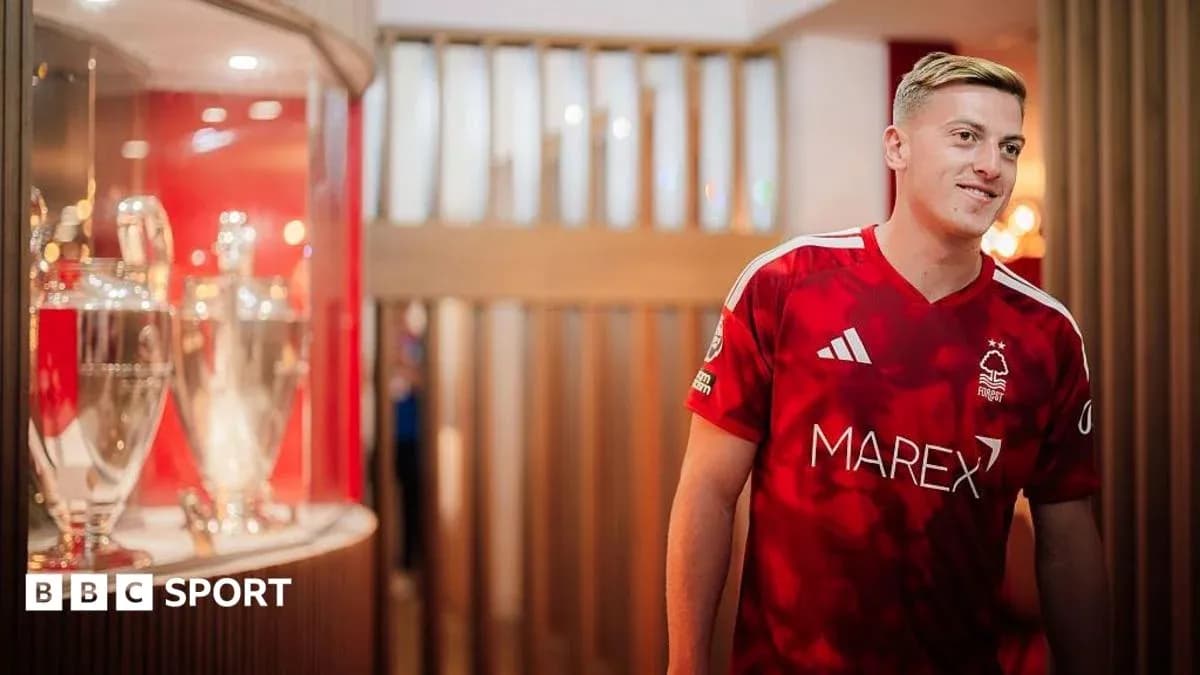 Joueur portant le maillot de Nottingham Forest près des trophées Joueur portant le maillot de Nottingham Forest près des trophées